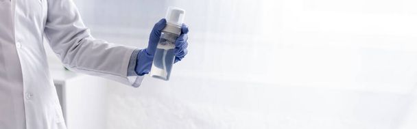 Teilansicht Laborassistentin in Latex-Handschuhhalterflasche mit Kosmetikprodukt, Banner - Foto, Bild
