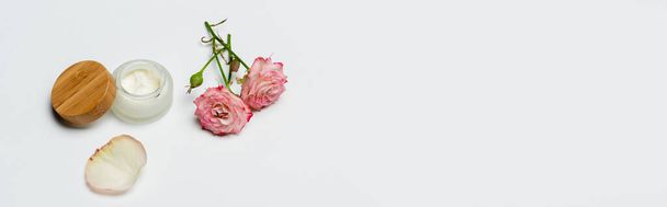 flores cor-de-rosa perto de recipiente com creme em branco, banner - Foto, Imagem