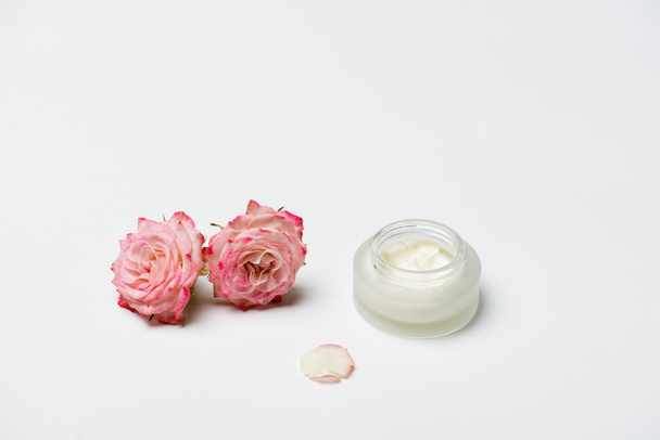 rosa rosas perto de recipiente com creme em branco - Foto, Imagem