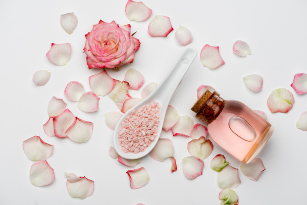 widok z góry kwiat w pobliżu płatków, różowa sól morska i butelka z wodą różaną na białym - Zdjęcie, obraz