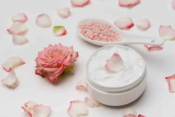 flower near petals, pink sea salt and container with cream on white - Fotografie, Obrázek