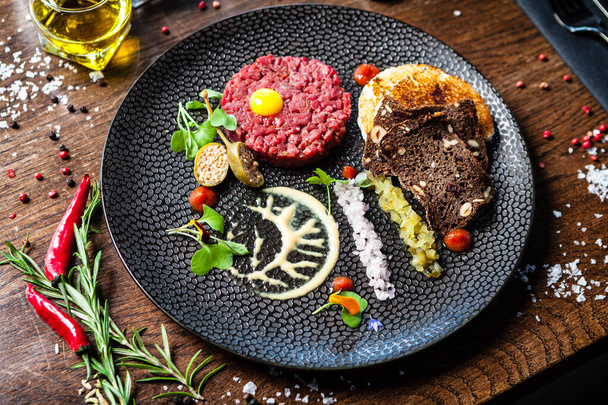 Beef tartare from Black Angus. Onion, quail egg, tomato sauce, mustard mayonnaise. Delicious healthy Italian traditional food closeup served for lunch in modern gourmet cuisine restaurant. - Photo, Image