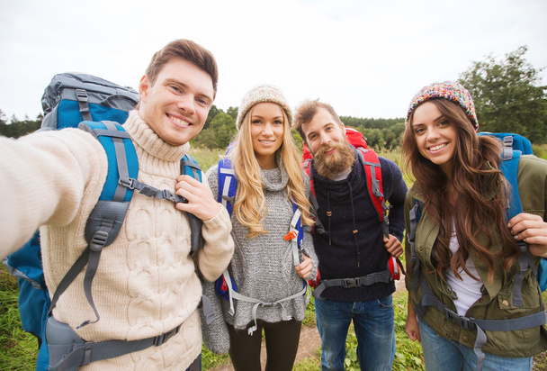 group of smiling friends with backpacks hiking - 写真・画像