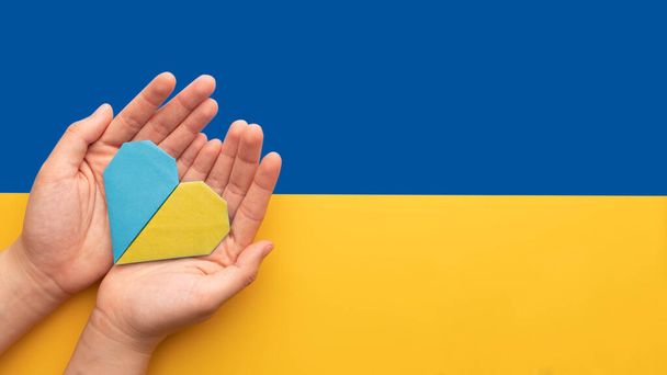 Postav se ukrajinské koncepci. Ruce drží modré a žluté srdce na pozadí Ukrajiny vlajky. Modlete se za mír na Ukrajině. - Fotografie, Obrázek