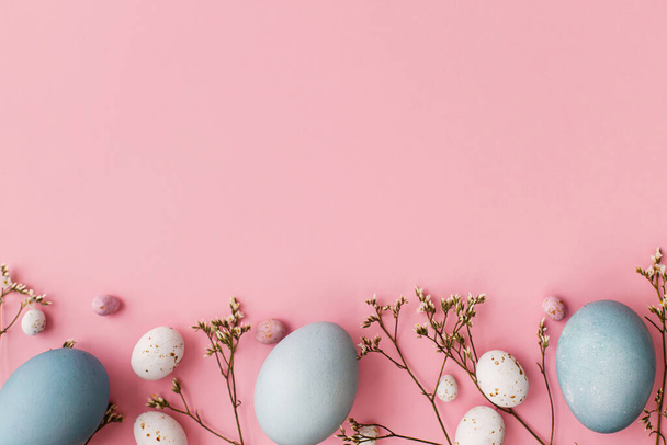 Easter eggs and flower flat lay on pink background with space for text. Modern natural dyed blue easter eggs and white flowers border on pink. Greeting card template, easter background - Photo, Image