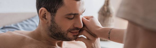 Tattooed woman touching shirtless boyfriend with closed eyes on bed, banner  - Valokuva, kuva