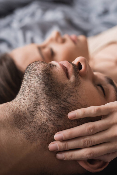 Blurred woman touching cheek of boyfriend on bed at home  - Zdjęcie, obraz