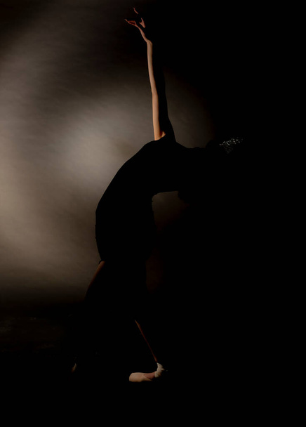 Κομψό σιλουέτα γυναίκα ποζάρει στο στούντιο, ενώ φοράει μαύρο φόρεμα και καπέλο - Φωτογραφία, εικόνα