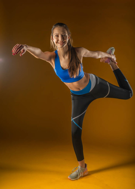 Fit woman stretching warming up - isolated yellow background - Foto, Imagem