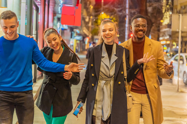 Grupo de amigos multirraciais estão rindo todos juntos enquanto caminham - Foto, Imagem