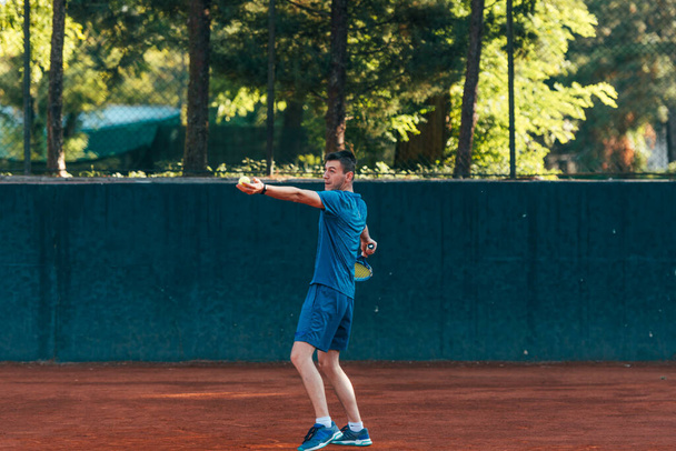 Jugador de tenis masculino equipado profesional golpeando duramente la pelota de tenis con un golpe de derecha - Foto, imagen
