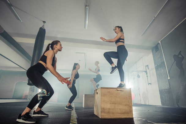 Groupe de conditionnement physique de femmes fortes ayant un entraînement interfonctionnel dans la salle de gym - Photo, image