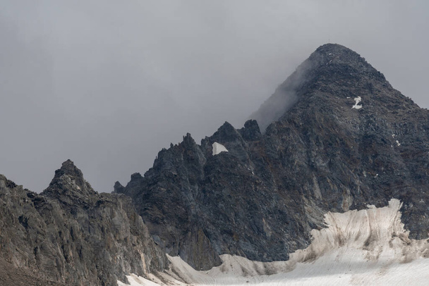 Primo piano di una vetta rocciosa che svetta nella nebbia delle Alpi svizzere. - Foto, immagini