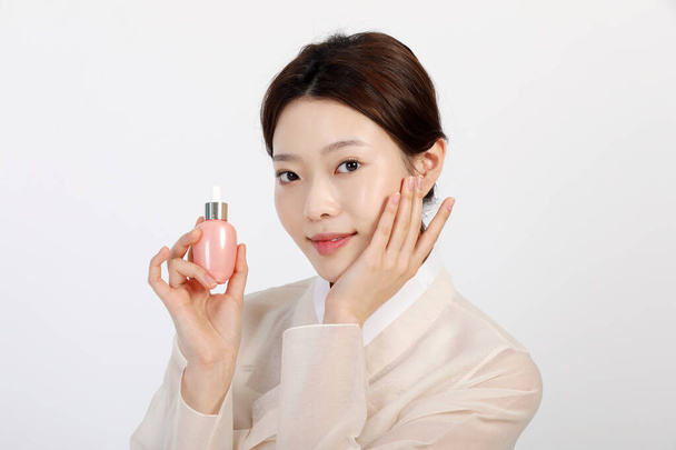 Asian Korean young woman wearing Hanbok Korean traditional clothes, holding cosmetics, beauty concept in studio - Φωτογραφία, εικόνα