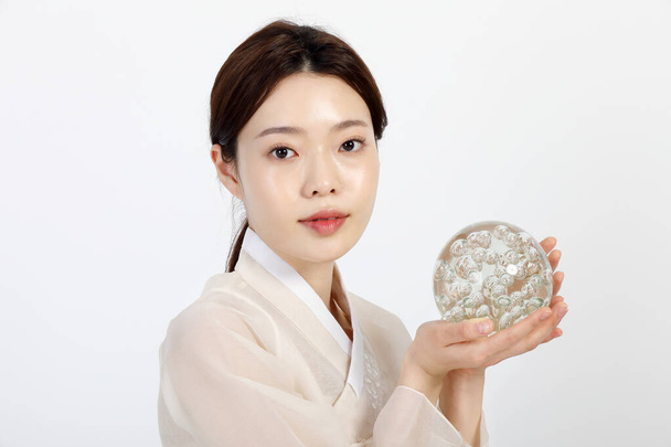 Asian Korean young woman wearing Hanbok Korean traditional clothes, holding collagen, beauty concept in studio - Φωτογραφία, εικόνα