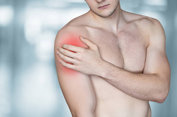 Patient showing sore shoulder on blurred background. - Zdjęcie, obraz