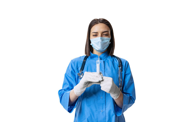 Studio shot of young serious woman, doctor wearing face mask and blue uniform isolated on white background. - Foto, afbeelding