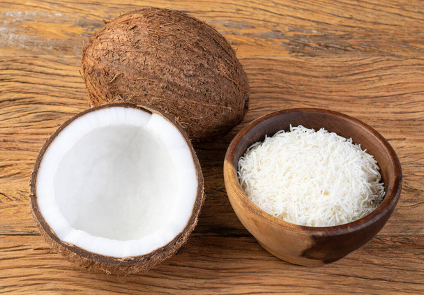 Strouhané kokosové vločky v misce s ovocem na dřevěném stole. - Fotografie, Obrázek
