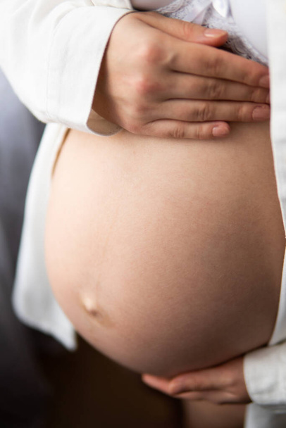 Νεαρή έγκυος γυναίκα αγγίζει την κοιλιά της, Κοντινό πλάνο ενός χαριτωμένο κοιλιά έγκυος. έγκυος γυναίκα με τα χέρια στην πλάτη. Έγκυος γυναίκα που κρατάει την κοιλιά της. απομονωμένο σε λευκό φόντο. - Φωτογραφία, εικόνα