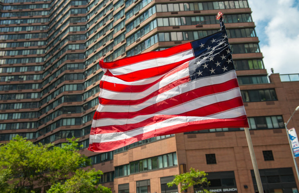 街の背景に建物に手を振っているアメリカの国旗 - 写真・画像