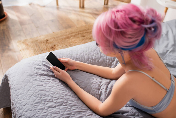korkea kulma näkymä nuori nainen värjätyt hiukset makaa sängyssä, kun juttelee älypuhelimeen - Valokuva, kuva
