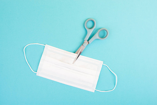 medical mask and scissors  on a blue background - Photo, Image