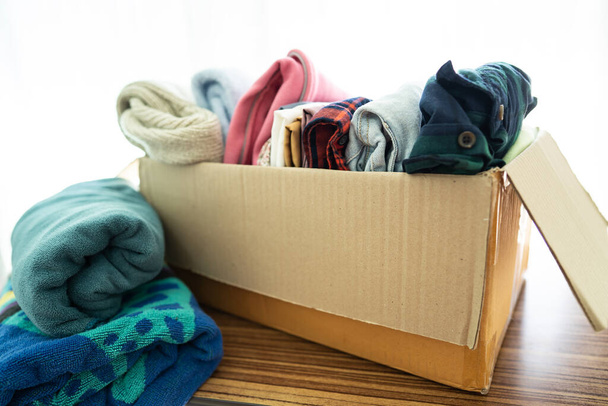 Donatie doos met gebruikte kleding thuis ter ondersteuning van hulp voor arme mensen in de wereld. - Foto, afbeelding