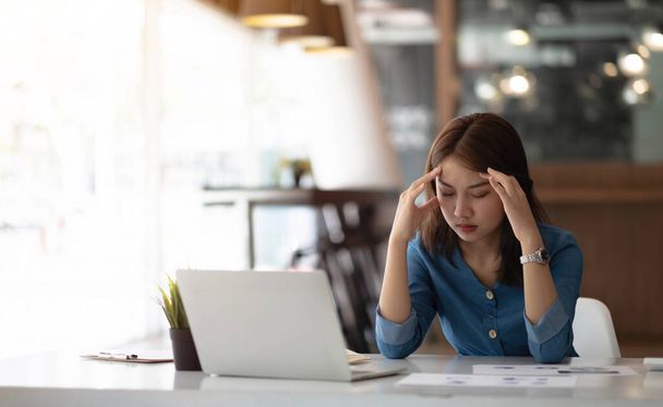 Imagen mujer asiática están estresados, dolor en los ojos, trabajar con su computadora portátil, tomando notas en la oficina - Foto, Imagen