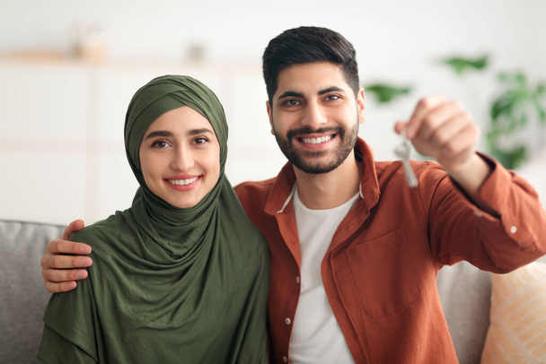 Feliz pareja de Oriente Medio mostrando nueva llave de la casa en el interior - Foto, Imagen