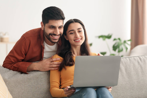 Arabic Spouses Using Laptop Computer Browsing Internet Sitting At Home - Φωτογραφία, εικόνα
