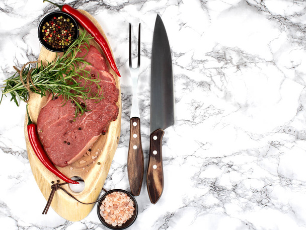 Rohe Steak Ribeye mit Gabel und Messer auf einem Steingrund. Freiraum für Ihren Text. Rustikaler Stil. - Foto, Bild