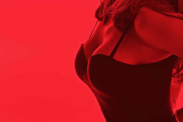 A business woman shows a close-up of a decollete. Office stylish sexy clothes. Red erotic toning - Foto, immagini