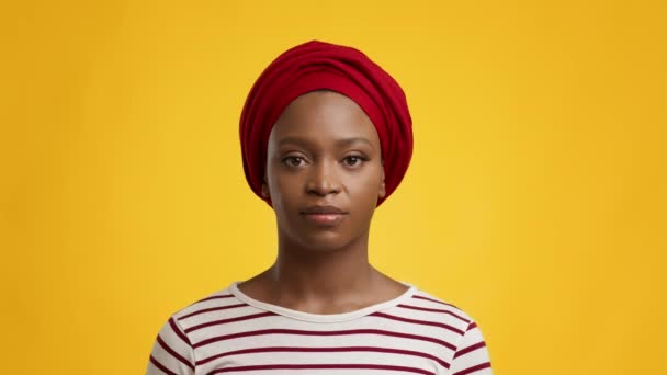 Retrato de una dama africana seria usando un abrigo rojo, fondo amarillo - Imágenes, Vídeo