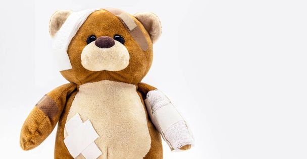 oso de peluche marrón con vendajes, animal herido de juguete, concepto de violencia o agresión - Foto, Imagen