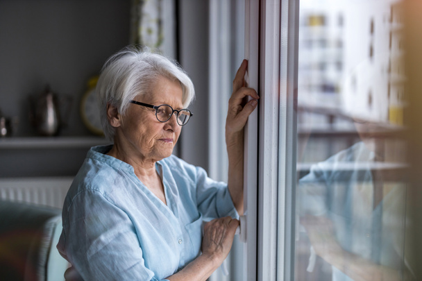 Seniorin schaut zu Hause aus dem Fenster - Foto, Bild