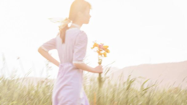 young woman in white dress with a bouquet of flowers on a background of the sunset - Fotoğraf, Görsel