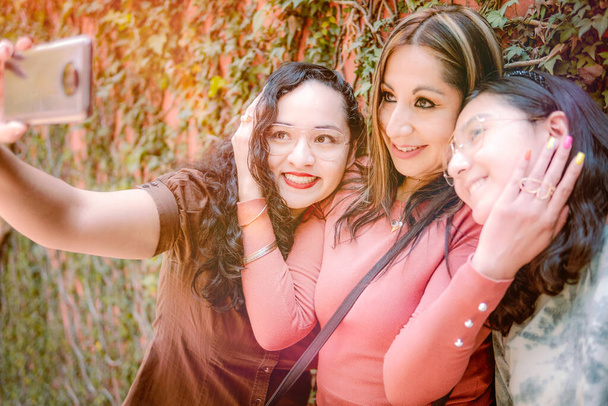 Sokakta selfie çeken üç kız birbirlerini çok sevdikleri için mutlu görünüyorlar. - Fotoğraf, Görsel