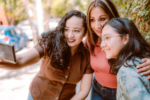 Drie meisjes nemen selfie op straat, kijken blij omdat ze zoveel van elkaar houden - Foto, afbeelding