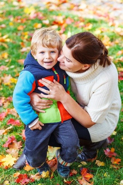 Молода мама і її маленький син обіймаються в осінньому парку
 - Фото, зображення