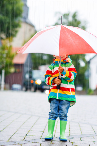 Söpö pieni poika keltainen sateenvarjo ja värikäs takki ulkona
 - Valokuva, kuva