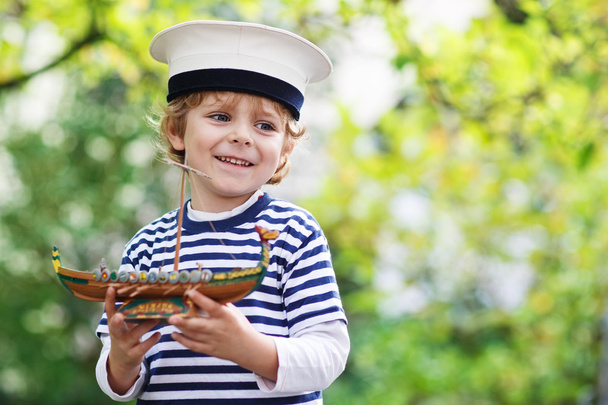 Happy child in skipper uniform playing with toy ship - Foto, Imagem