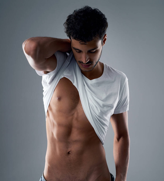 These abs were made for showing. Studio shot of a handsome young man posing against a grey background. - 写真・画像