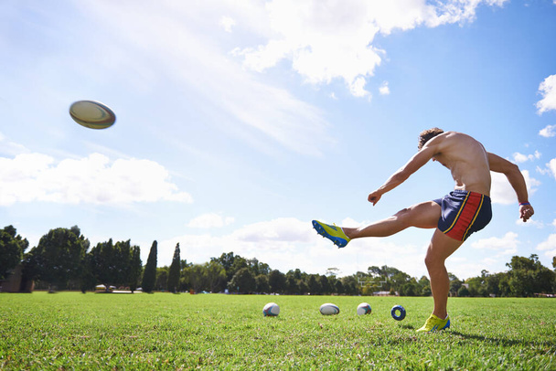 To je ale krásný kop. Široký akční záběr mladého muže kopající rugby míč. - Fotografie, Obrázek