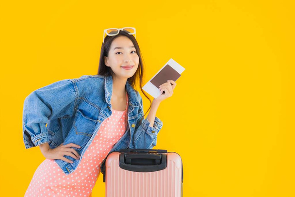 Ritratto bella giovane donna asiatica con bagaglio borsa da viaggio con passaporto e biglietto d'imbarco su sfondo giallo isolato
 - Foto, immagini