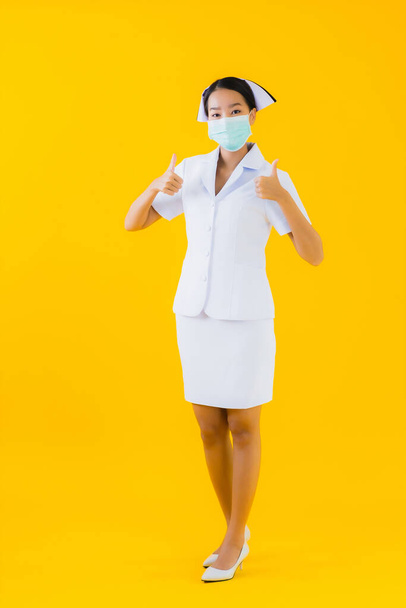 Ritratto bella giovane donna asiatica infermiera tailandese indossare maschera per proteggere covid19 o coronavirus e mostrare gel alcolico su sfondo giallo isolato
 - Foto, immagini