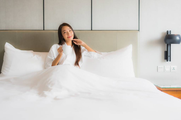 Porträt schöne junge Asiatin mit Kaffeetasse im Schlafzimmer - Foto, Bild