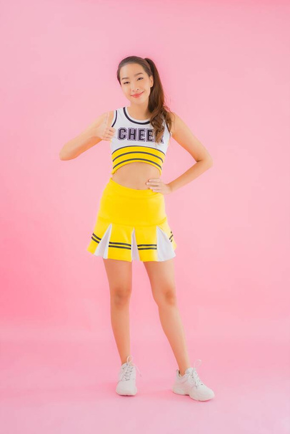 Porträt schöne junge asiatische Frau Cheerleader auf rosa isolierten Hintergrund - Foto, Bild