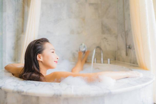 Retrato bonito jovem asiático mulher relaxar tomar um banho na banheira no banheiro interior
 - Foto, Imagem