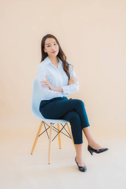Ritratto bella giovane donna asiatica sedersi sulla sedia con computer portatile o smartphone per lavoro - Foto, immagini