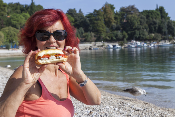 Όμορφη γυναίκα απολαμβάνοντας φρέσκα θαλασσινά σάντουιτς τρόφιμα - Φωτογραφία, εικόνα